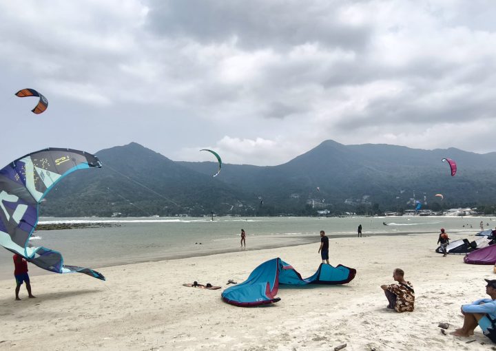 Kitesurfers riding strong winds at Chaloklum Beach on a busy day in Koh Phangan, Thailand