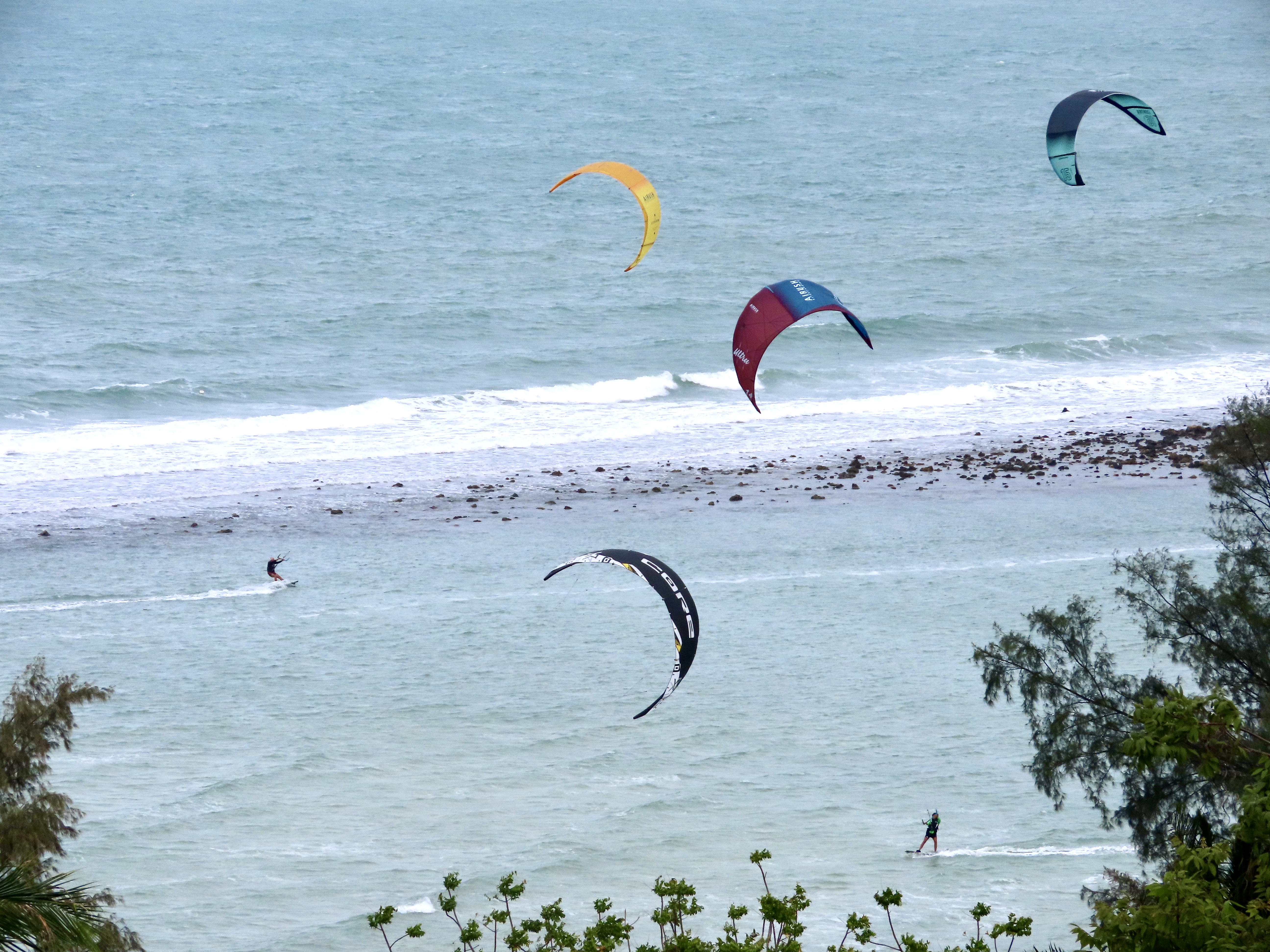 Aerial view of Chaloklum Bay showing the protective reef and flat water lagoon with kitesurfers riding.
