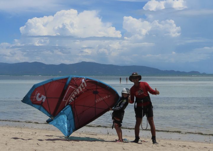 Kitesurfing instructor and young girl student posing with a kite on the beach at Siam Pro Kite, Koh Phangan, Thailand.