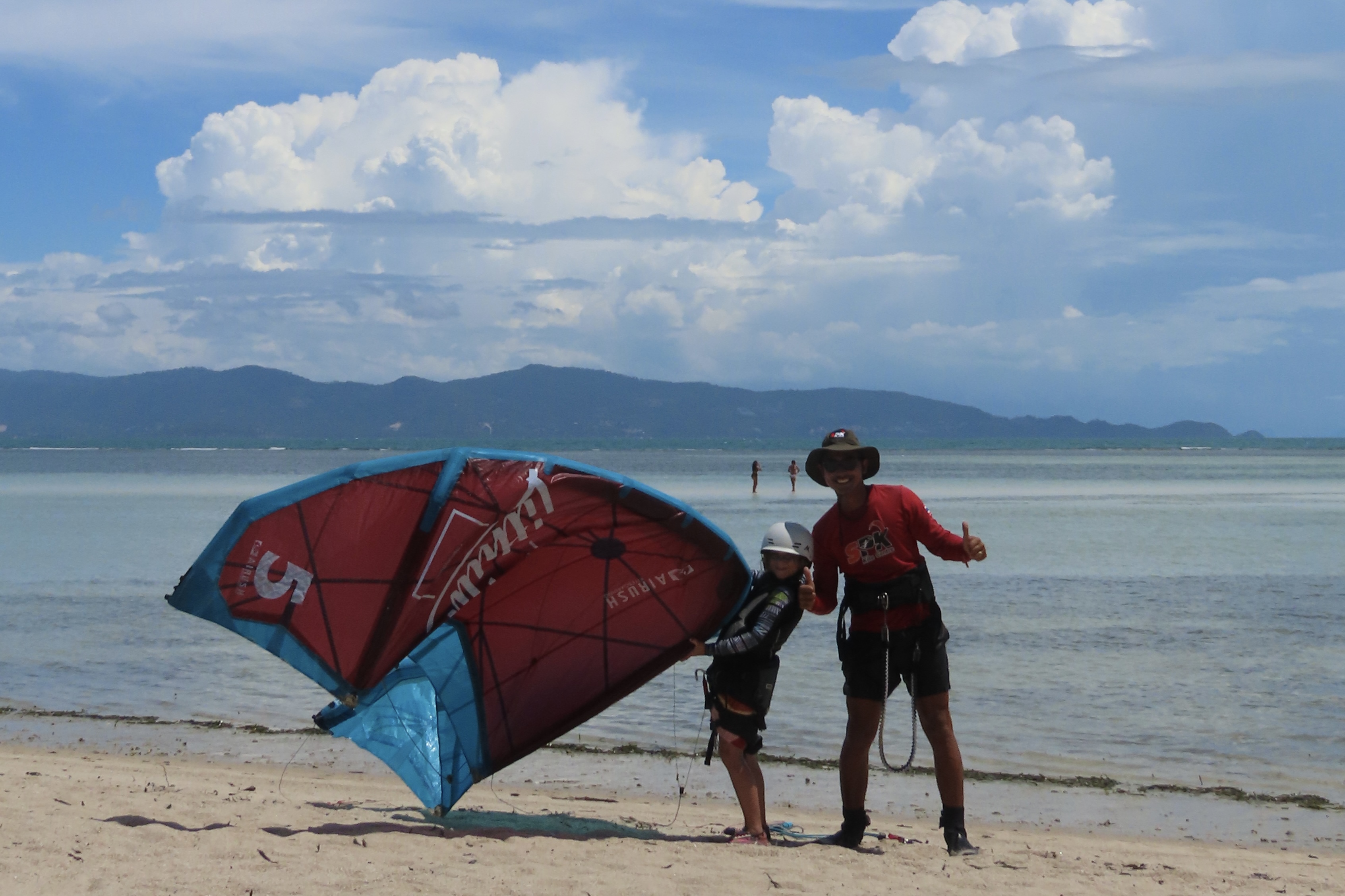 Kitesurfing instructor and young girl student posing with a kite on the beach at Siam Pro Kite, Koh Phangan, Thailand.