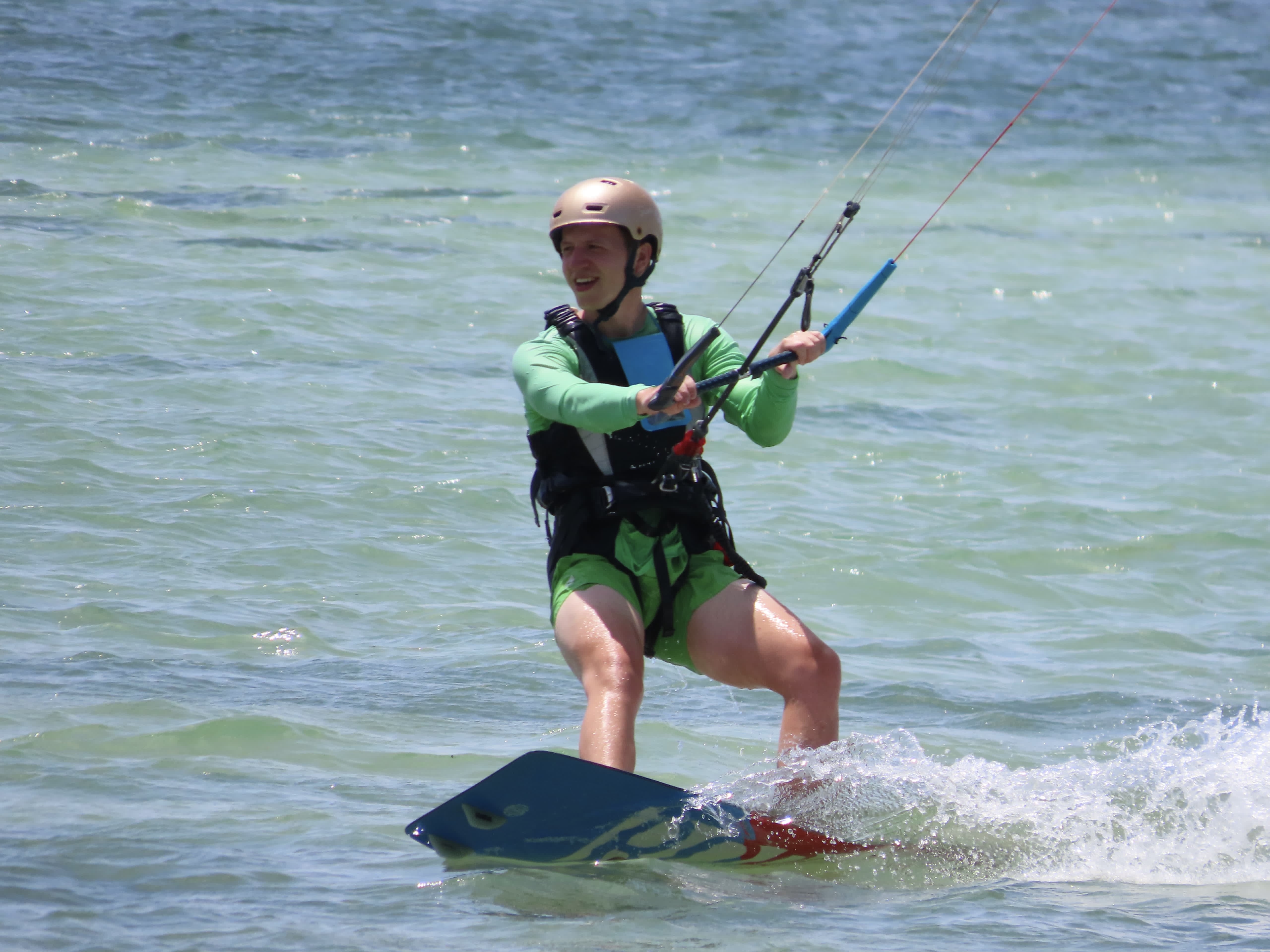 Man learning to kitesurf during a beginner lesson on Koh Phangan Island, Thailand, with an instructor guiding him on turquoise lagoon waters.